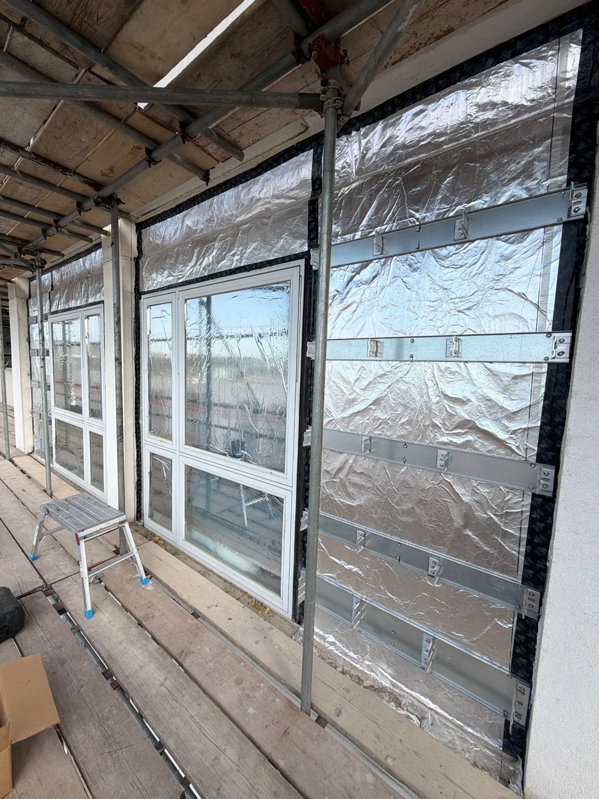 Support rails and foil-faced façade build-up during current installation