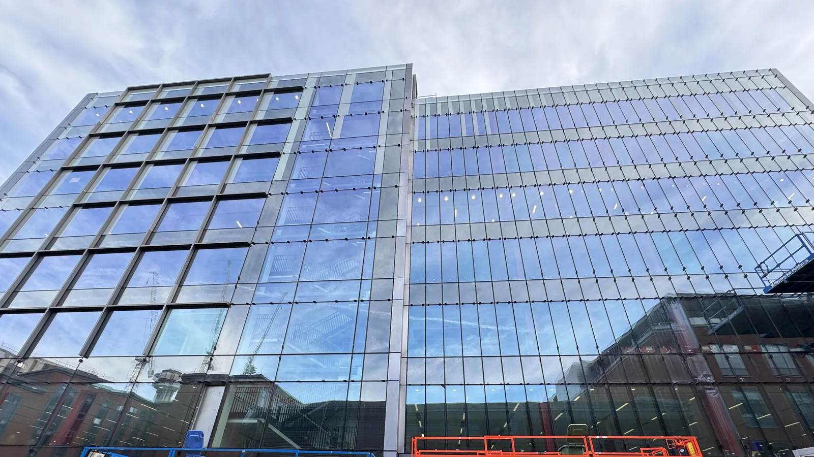 Commercial glazed facade works with MEWP access on an active construction site.