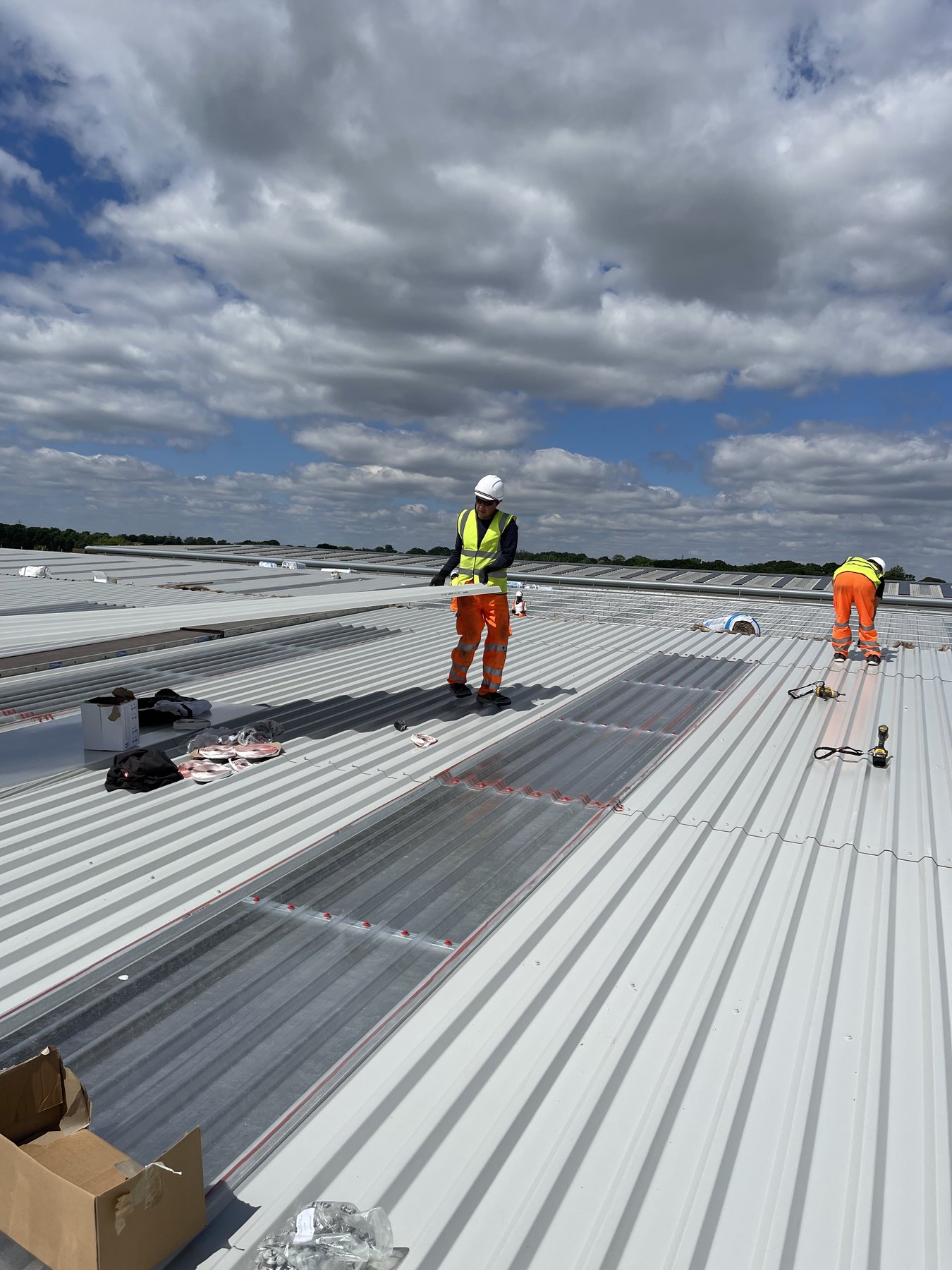 Workers installing roof sheets on a large data centre roof area