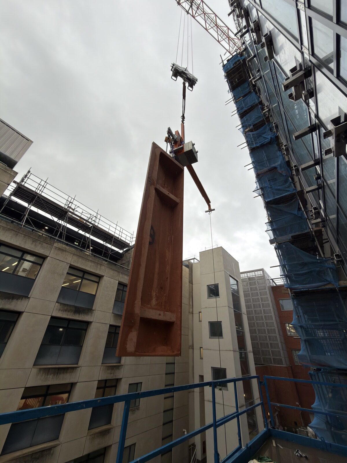 Large GRC facade panel lifted by crane near curtain wall glazing
