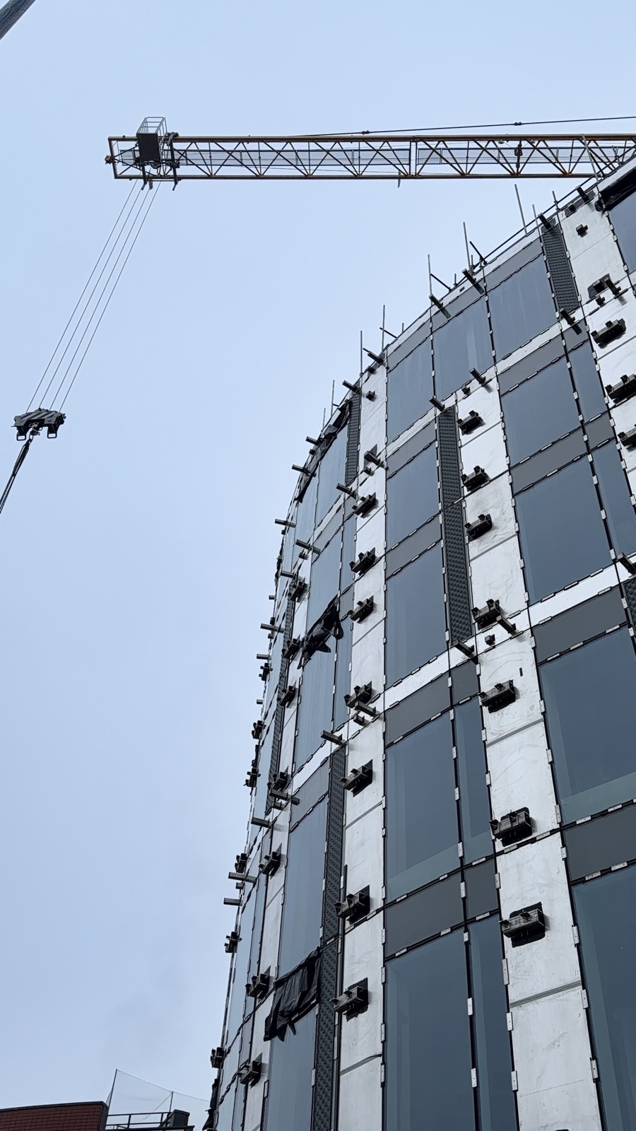 Tower crane above curtain wall facade prepared for GRC panel installation