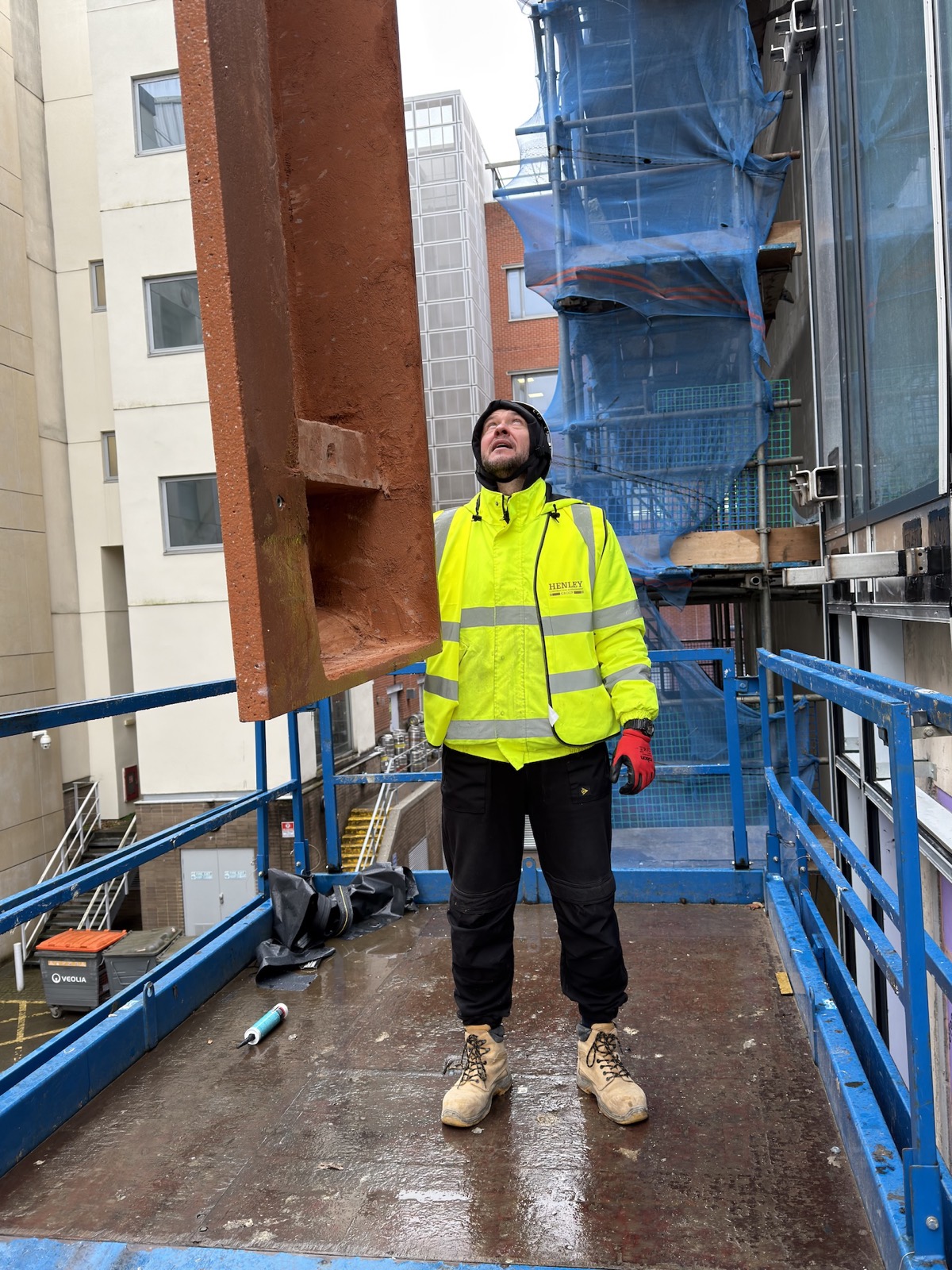 Installer guiding suspended GRC facade panel on a live site